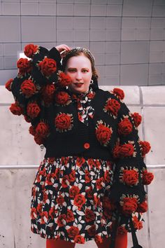 a woman in a dress with flowers on it's shoulders and hands behind her head