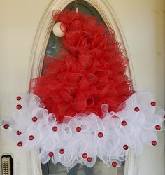 a red and white wreath hanging on the front door