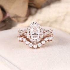 Unique Pear Cut Moissanite Engagement Ring Set Rose Gold Moissanite Bridal Set Moissanite Halo Wedding Ring Pearl Curved Wedding Band Women ✦ Handmade, high-quality item ✦ Material: SOLID 10K/14K/18K GOLD ( can be made in yellow/white/rose gold ) ✦Engagement ring ✦ Center stone: Moissanite ✦ Size/Weight: 6*9mm ✦ Color: DEF color ✦ Cut: Pear Shaped ✦ Side stones: Natural Diamonds ✦ Weight: About 0.581ct  ✦ Color: G-H ✦ Clarity: SI-VS ✦ Or Side stones Moissanite: 0.581ct ✦ Band Width: Around 1.5mm Diamond Ring With Pearl Side Stones, Pearl Wedding Bands, Pearl Wedding Ring, Wedding Band Women, Moissanite Engagement Ring Set, Pearl Engagement Ring, Ring Pearl, Moissanite Bridal Sets, Wedding Rings Halo