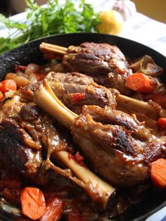 a skillet with meat, carrots and onions in it