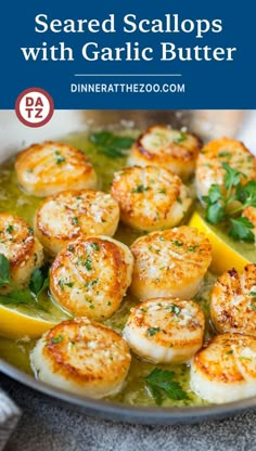 garlic butter scallops in a pan with lemon wedges