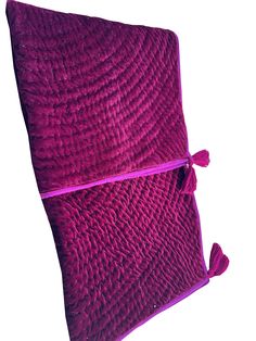 a purple pillow with tassels on the bottom and one pink zippered closure