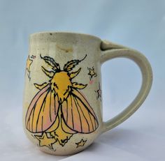 a ceramic mug with a yellow and black bee on it's side, against a white background