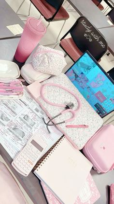 various items are arranged on a table with pink and white accessories, including a laptop