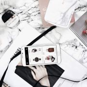 a cell phone sitting on top of a white table next to a laptop and other items