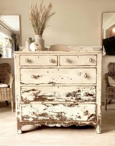 an old white dresser with some plants on top