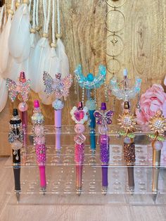 there are many different types of pens in the display case with beads and bows on them