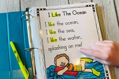 a child's hand holding a lit candle next to an open book with the words i like the ocean on it