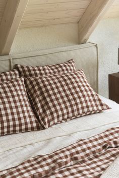 a bed with brown and white checkered pillows on it's headboard in a bedroom