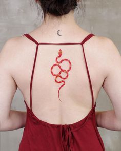 the back of a woman's red dress with a snake tattoo on her chest