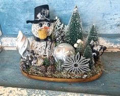 a snowman made out of wire and other christmas decorations on a wooden table with blue paint