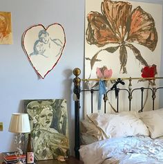 a bed room with a neatly made bed and paintings on the wall