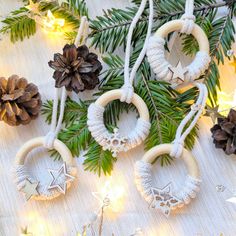 some ornaments are hanging from a tree with pine cones and lights around them on a table