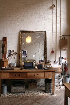 a room with a desk, mirror and other items on the table in front of it