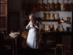 an old man playing the violin in a room full of guitars and other musical instruments