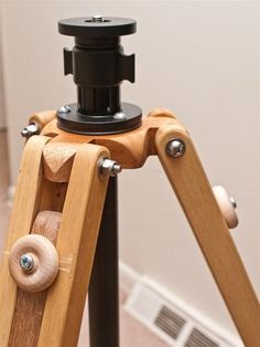 a wooden tripod with a camera attached to it's base and two wheels