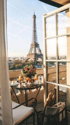 a balcony with a table and chairs overlooking the eiffel tower