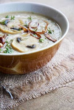 a close up of a bowl of soup on a cloth with spoons and napkin