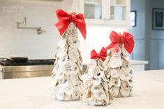 two christmas trees made out of seashells with red bows on them sitting on a kitchen counter