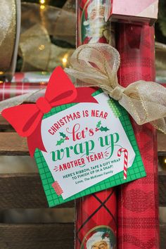 a christmas cracker wrapped in red and green paper with a bow on it, sitting next to a wooden box