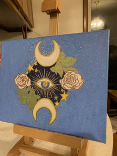 an easel with a painting on it that has roses and the moon painted on it