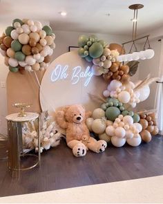 there is a teddy bear sitting next to balloons and other decorations on the wall behind it