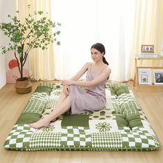 a woman sitting on top of a green and white floor mat