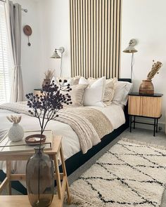 a bed room with a neatly made bed next to a night stand and two side tables