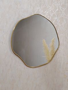 a mirror that is on the wall next to a vase with some flowers in it