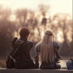 two people sitting on the ground with long hair