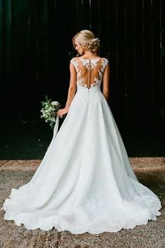 a woman standing in front of a black wall wearing a wedding dress