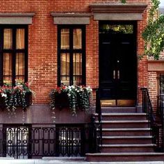 an old brick building with flowers in the window boxes and wrought iron railing on the sidewalk