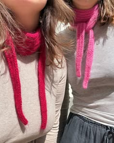 two young women wearing knitted scarves and hats, one with her mouth open