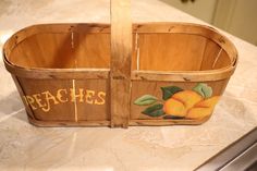 a wooden basket with peaches painted on the side sitting on top of a counter