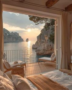 a bedroom with a view of the ocean and cliffs at sunset or sunrise from outside