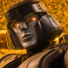 a close up of a robot with yellow eyes and an orange light in the background