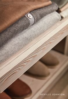 a pair of shoes are sitting on top of a book shelf next to some folded books