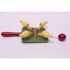 three plastic birds on a green board with a red object in the foreground and a cherry on the other side