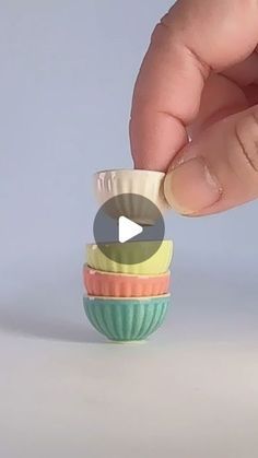 a hand is holding a small cupcake in it's right hand and placing the top part on another cupcake