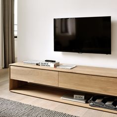 a flat screen tv mounted to the side of a wooden entertainment center in a living room