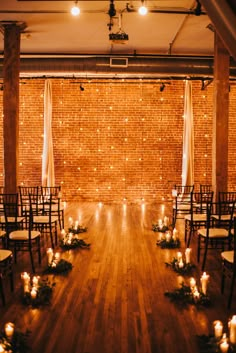 an empty room with chairs and candles on the floor in front of a brick wall