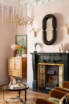 a living room filled with furniture and a chandelier hanging from the ceiling over a fire place