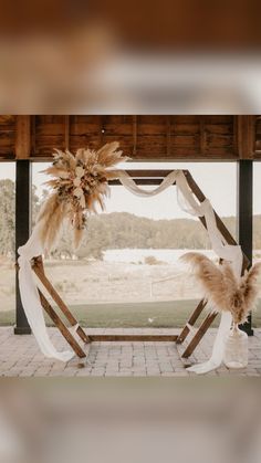 the wedding arch is decorated with feathers and ribbons