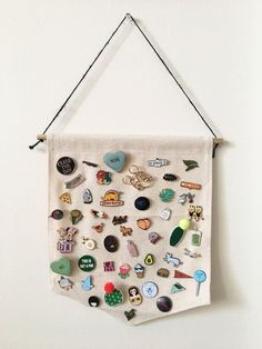 a white wall hanging with various pins and magnets on it's back side