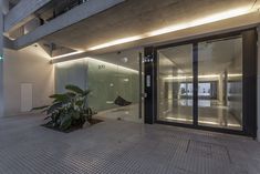 the entrance to an office building with large glass doors and plants in front of it