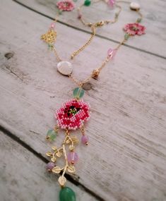 a beaded necklace with flowers and leaves on it sitting on top of a wooden table