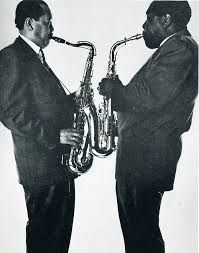 two men in suits are playing the saxophone