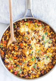 a skillet filled with mexican rice and beans, topped with a wooden spatula