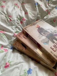 three books sitting on top of a bed next to each other in front of a white sheet