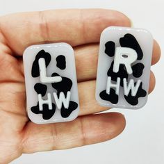 two black and white earrings with the letter hw in it's middle hand